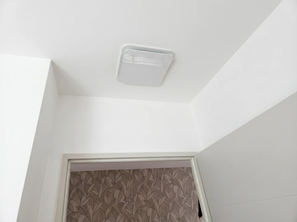 Extérieur résidentiel, installation d'une pompe à chaleur air/air sur socle béton, contre façade crépi beige, proche d'un garage
