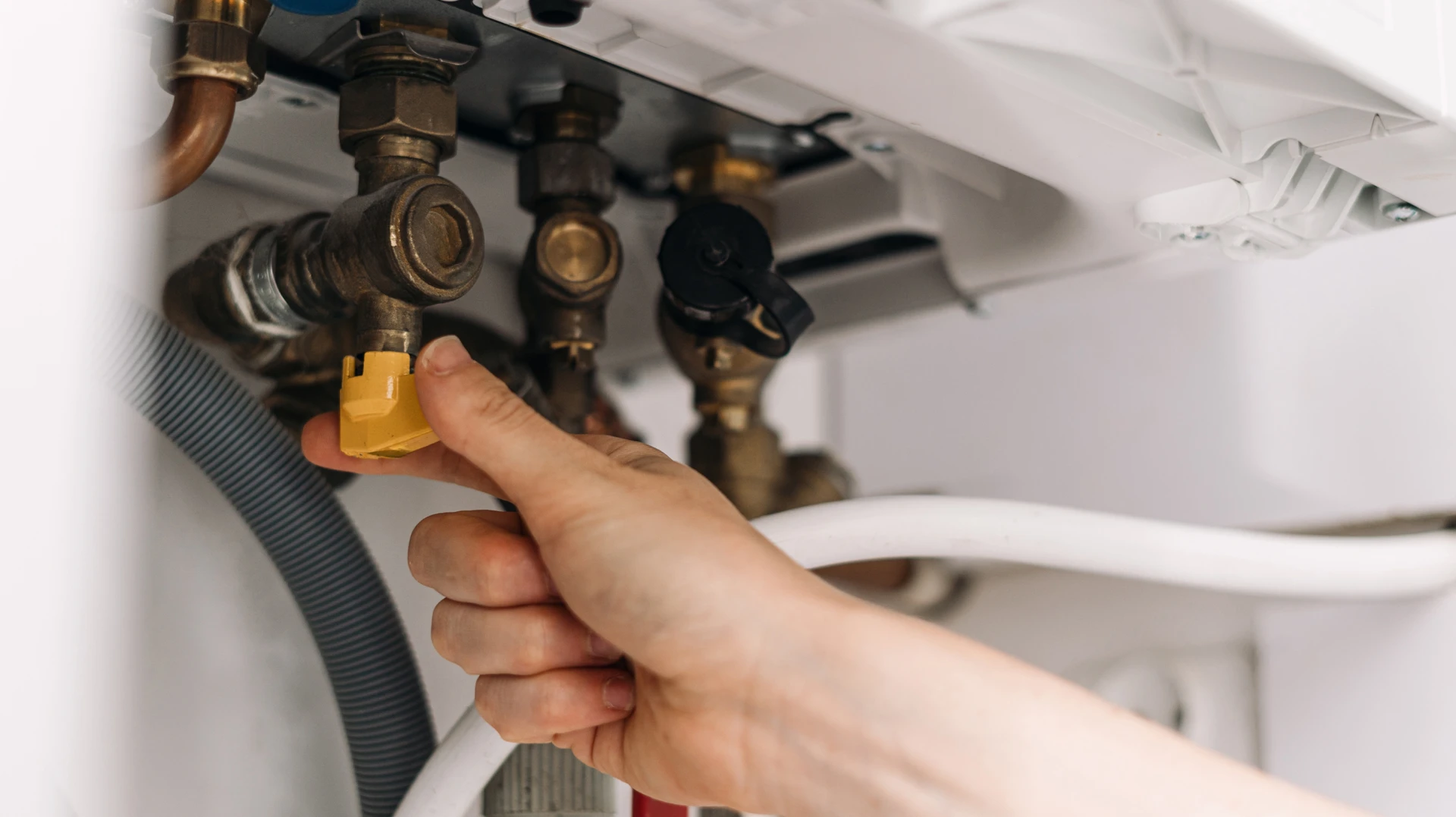 Technicien professionnel en uniforme bleu effectuant une intervention de maintenance ou dépannage sur une unité intérieure de climatisation réversible ou pompe à chaleur installée chez un particulier, avec outils en main, concentré sur son travail dans un contexte domestique montrant la disponibilité et la réactivité du service d'urgence.