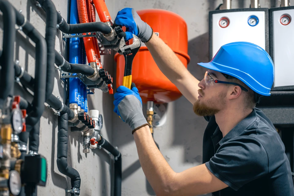 Technicien HVAC en uniforme vert travaillant sur système de chauffage/climatisation dans intérieur résidentiel